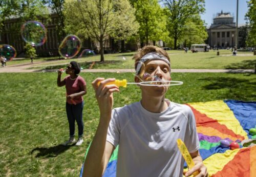 student blowing bubbles on campus
