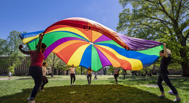 students with a rainbow parachute on campus