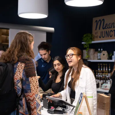 Student taking coffee order of customer at cafe