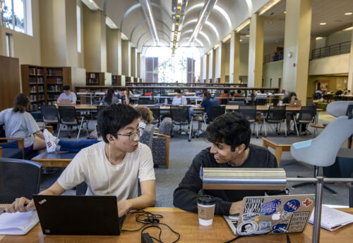 Two students sitting in Davis Library with laptops.