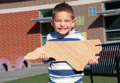 Child holding North Carolina state block.