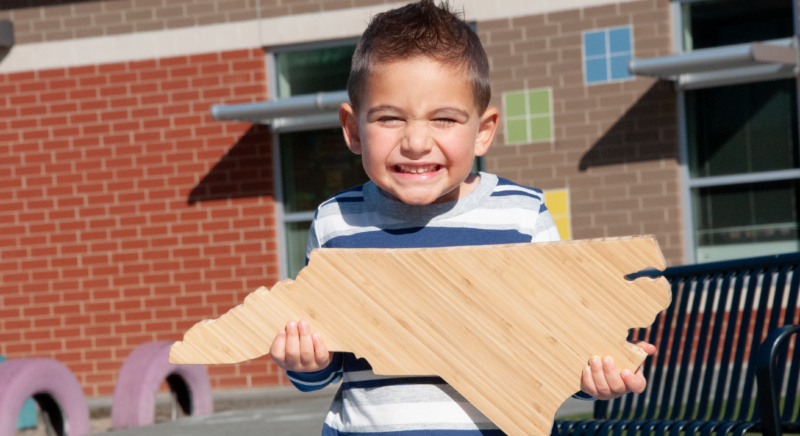 Child holding North Carolina state block.