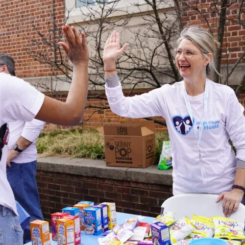 Parent volunteer high fives a Carolina student.
