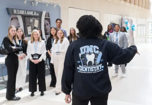A student wearing a UNC Dentistry hoodie leads a tour group