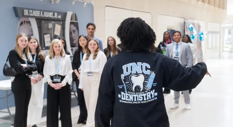 A student wearing a UNC Dentistry hoodie leads a tour group