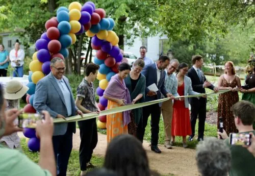 Members of the AIC in front of a balloon arch cutting a ribbon in celebration.