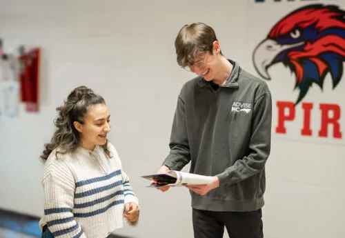 Two people looking at a pamphlet and smiling.
