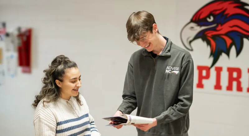 Two people looking at a pamphlet and smiling.