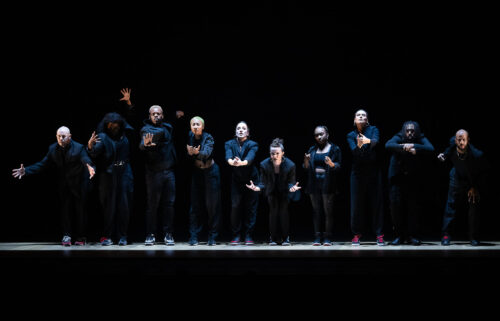 Dancers on a dark stage with upper bodies illuminated