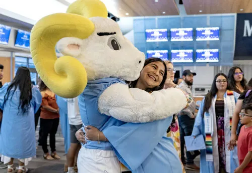 Graduate hugs Ramses during the Carolina Latinx Center's annual Exitos Awards Ceremony