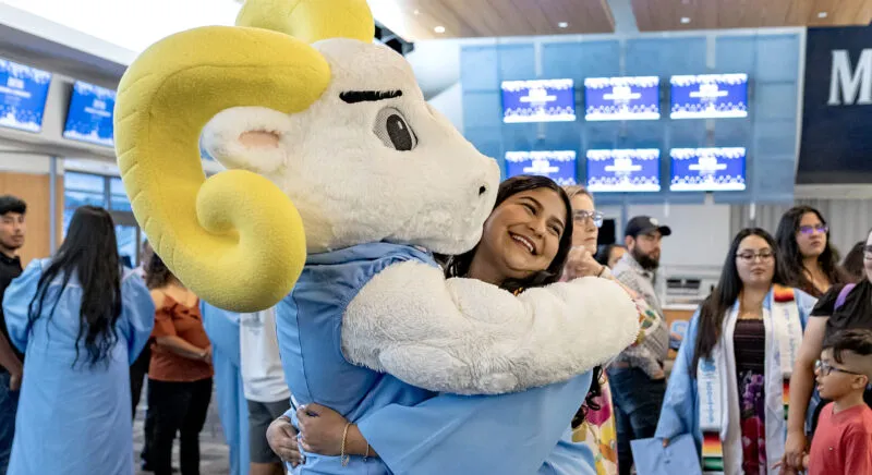 Graduate hugs Ramses during the Carolina Latinx Center's annual Exitos Awards Ceremony
