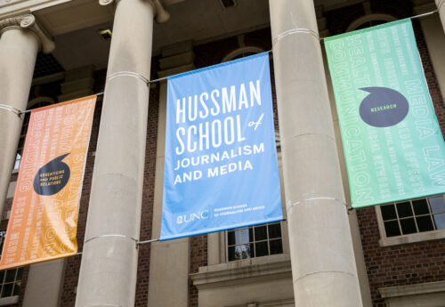 A close up of three banners outside of Carroll Hall