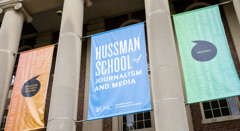 A close up of three banners outside of Carroll Hall