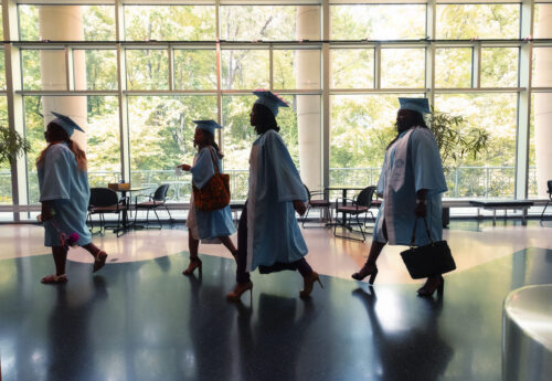 Graduating students walking through a hallway.