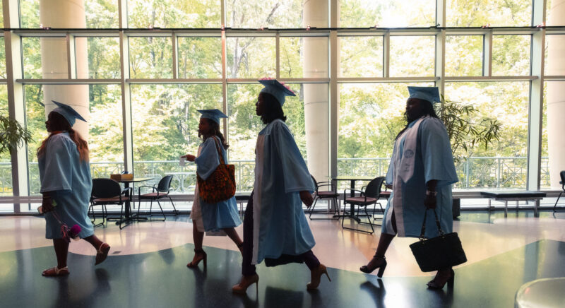 Graduating students walking through a hallway.