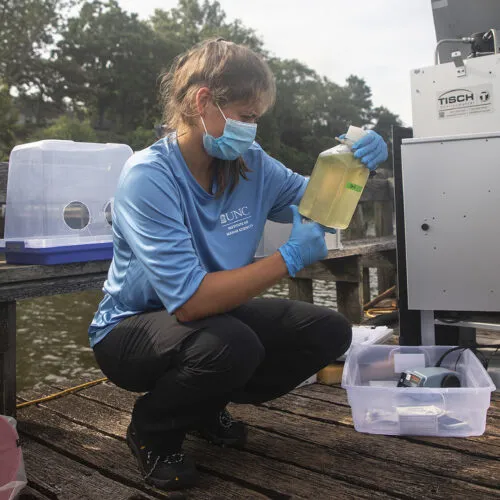 A Gillings School of Public Health student observes water levels in a jug on site.