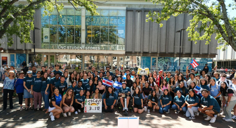 Large group of individuals holding posters posed for a photo on campus.