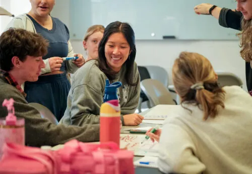 Six students working around a table and smiling