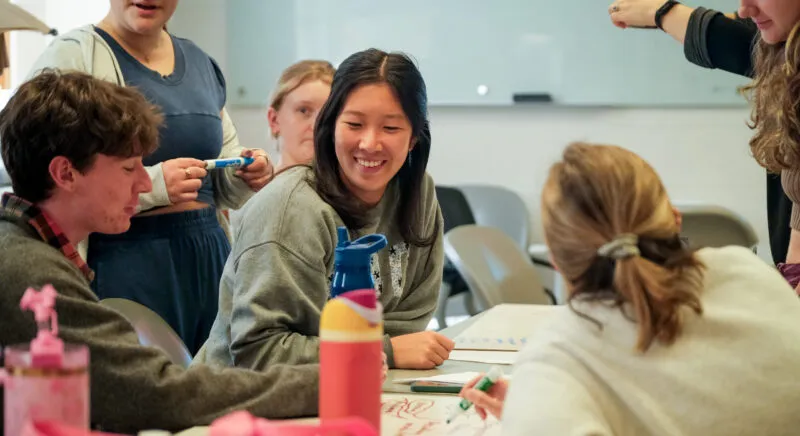 Six students working around a table and smiling