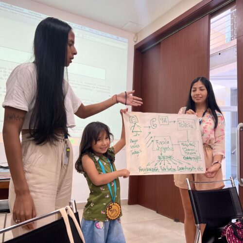 UNC School of Social Work Practicum students present a poster at the front of the classroom with a young child assisting.