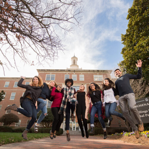 Gillings School of Public Health students jump outside of their building.