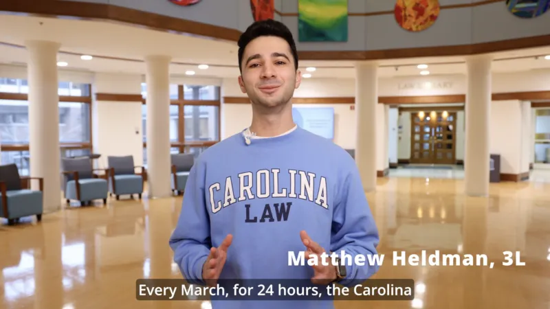 Matthew, 3L in a Carolina Law crew neck sweater