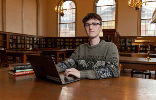 Carolina Covenant Scholar Sonny Griffith sitting at a table with his laptop open in the library