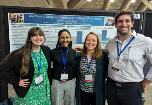 Four students posing in front of a project board