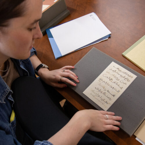 A young woman studies a document written in a foreign language.