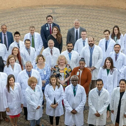 A group of UNC Health doctors wearing white coats looking overhead