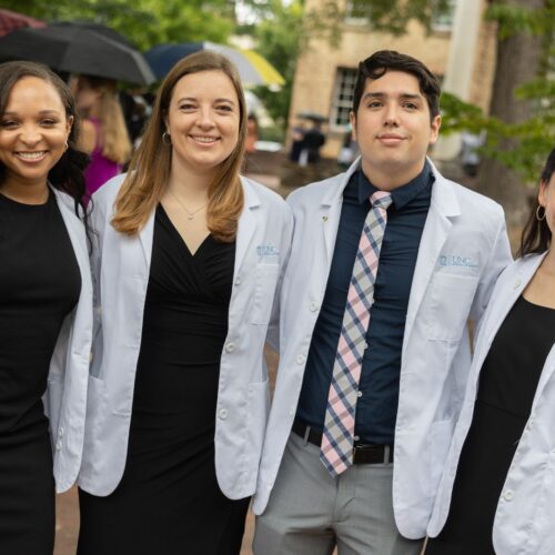 Four School of Medicine students standing together in white coats