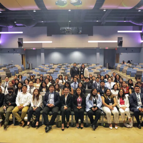 Large group of people wearing professional clothing seated in an auditorium.
