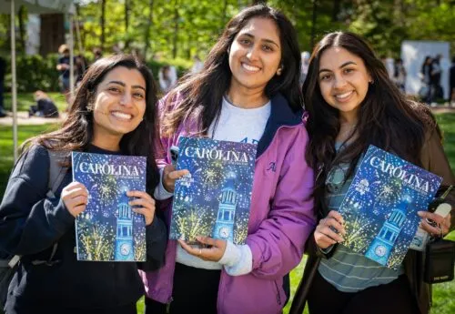 Students smile while holding copies of the Carolina Alumni Review