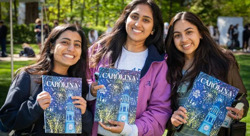 Students smile while holding copies of the Carolina Alumni Review