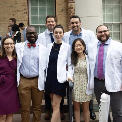 Graduate students smiling in their white coats.