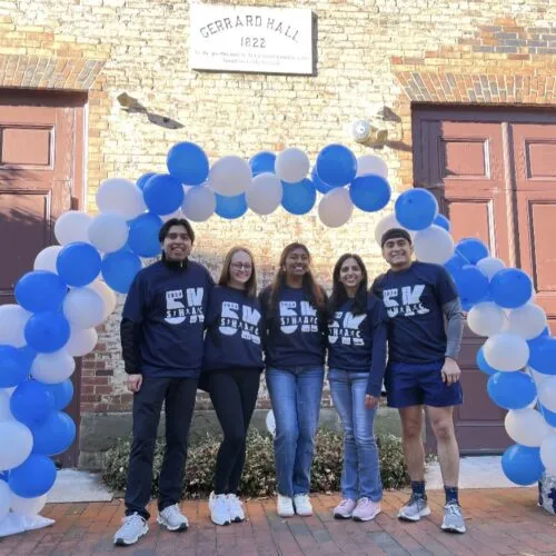 Students stand under a Carolina Blue balloon arch.