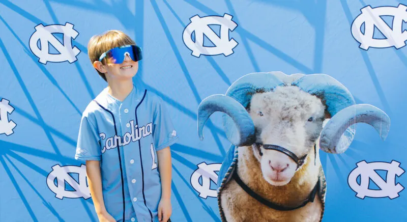 UNC-Chapel Hill baseball fan poses for photos with a cardboard cutout of Rameses at Boshamer Stadium prior to a game against Louisville on March 22, 2026 in Chapel Hill, NC. The activity was part of a promotion for GiveUNC, Carolina’s annual day of giving